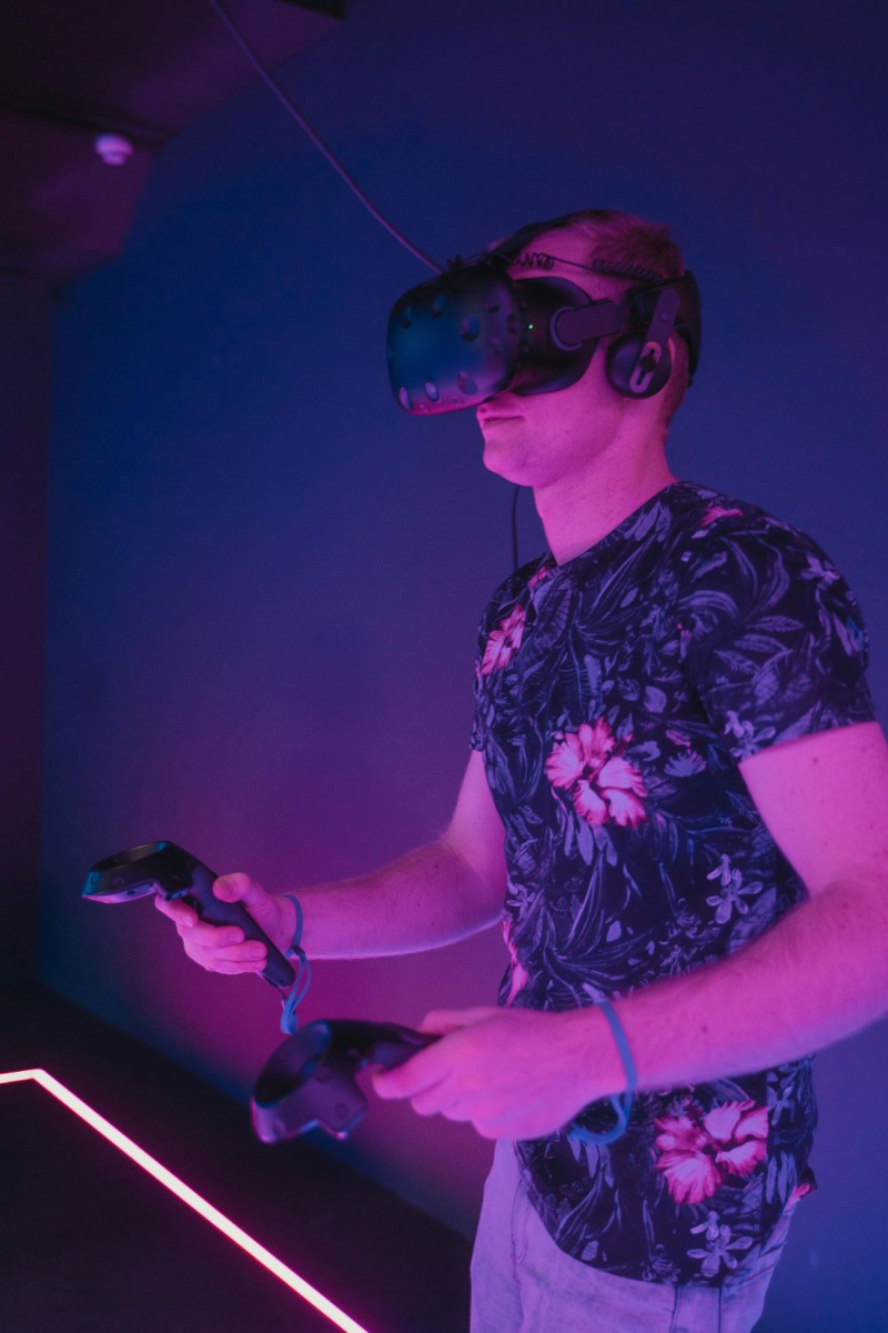 Person using a wireless VR headset and controllers in a neon-lit room